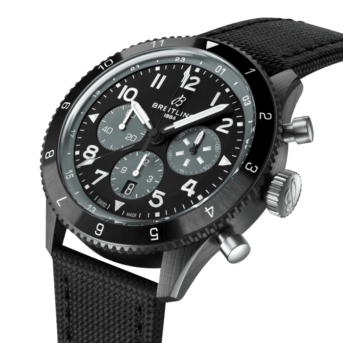 From brave first takeoffs to the birth of commercial air travel, Breitling’s history is inseparable from that of flight. In the 1930s, Breitling’s Huit Aviation department made its name inventing precision cockpit clocks. Two decades later, it introduced yet another novel flight instrument, this time in wearable form: the Ref. 765 AVI. That pioneering pilot’s watch provided the technical backdrop for today’s Super AVI, a collection inspired by the rugged spirit of famed early aircraft.
The Super AVI Mosquito honors one of those legends. In an era when aluminum and steel shortages were common, the engineers behind the de Havilland Mosquito made use of a still plentiful material: wood. The “Wooden Wonder” caused shockwaves when it outperformed its metal contemporaries to become one of the fastest planes built between 1940 and 1950. Its superior maneuverability allowed it to multitask in roles as far ranging as light bomber, transport, and photographic reconnaissance aircraft. This Super AVI Mosquito gets its inspo from the Night Fighter 2, an all-black two-seater aircraft meant to slip stealthily through the night sky.
As a true pilot’s watch designed to withstand the rigors of a vintage cockpit, the Super AVI Mosquito features large, highly legible Arabic numerals on the dial and bezel.
The overall black ceramic case contrasts strikingly with the titanium pushers, crown, caseback, and buckle. The knurled bezel provides optimal grip, even in a pilot’s gloved hands. The military-leather strap gives a nod to classic flight gear. Pilots and other travelers will appreciate the ability to track a second time zone using the 24-hour marking on the inner bezel and the white-tipped GMT hand. The engine of the Super AVI is the COSC-certified Breitling Manufacture Caliber B04 movement, which provides approximately 70-hours of power reserve.